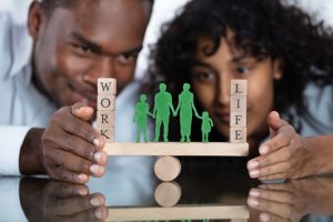 Two people balancing a family, with the words "work" on the left, and "life" on the right